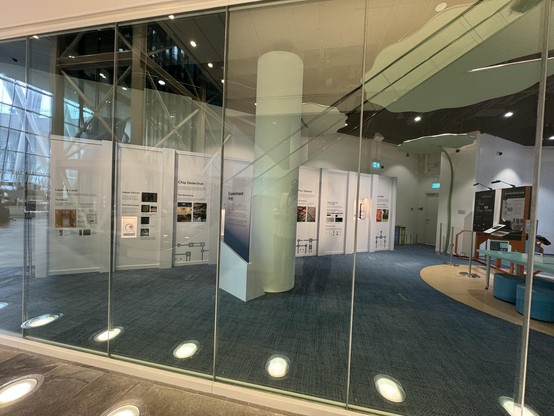 Museum exhibit with photos of decapped chips and lab equipment seen through a floor to ceiling glass window