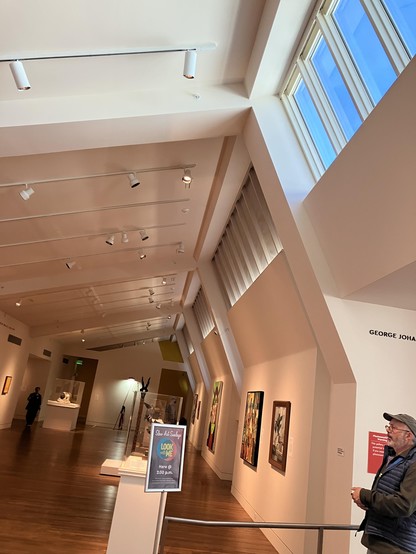 photo of a long art gallery with an angled wall and windows providing light near the top