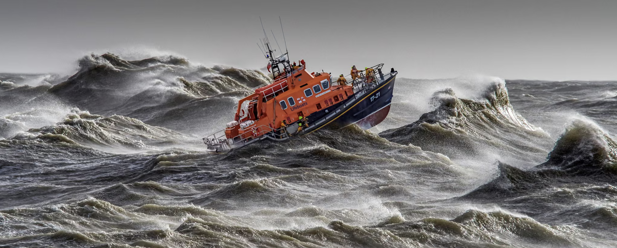 A British RNLI lifeboat amid massive breaking waves.
