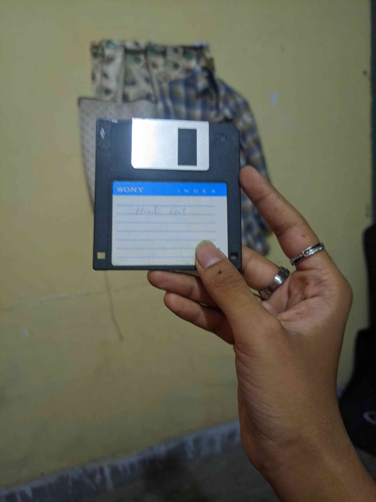 A hand  holding a floppy disk with Hindi fonts in it. This photo was taken 2-3 weeks ago.
