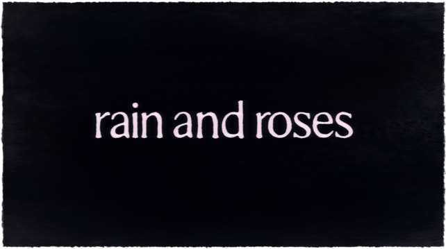 the text painted "rain and roses" on a dark painted background
the text is in a font that could be described as times new roman but not completely sans-serif